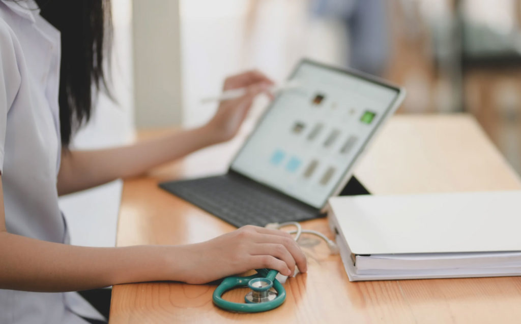 a doctor sitting at a desk with a stethoscope and computer