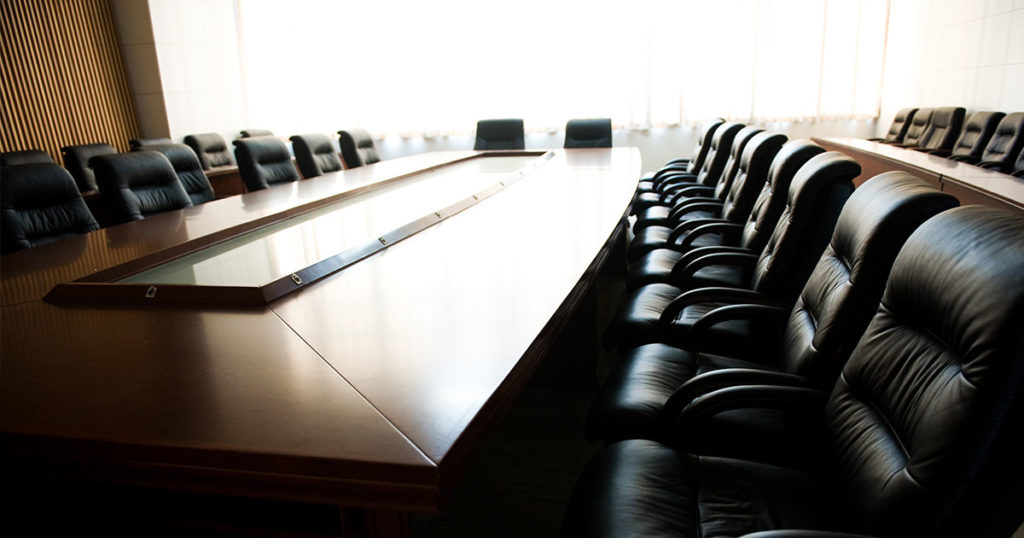 a company boardroom with large wooden table and leather chairs