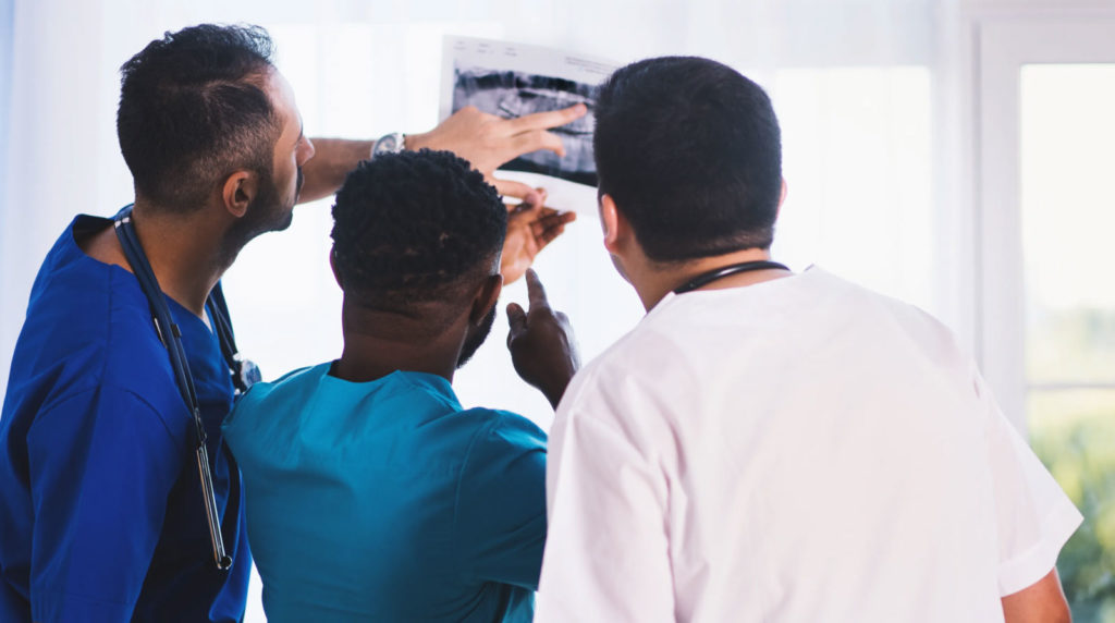 3 doctors standing discussing patient x-ray result