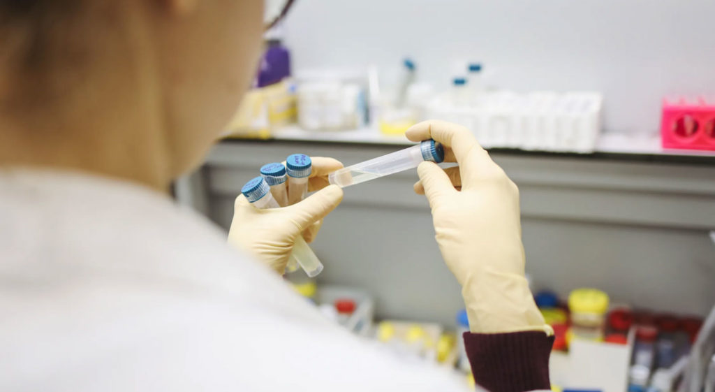 a scientist in a laboratory wearing a lab coat holding DNA samples