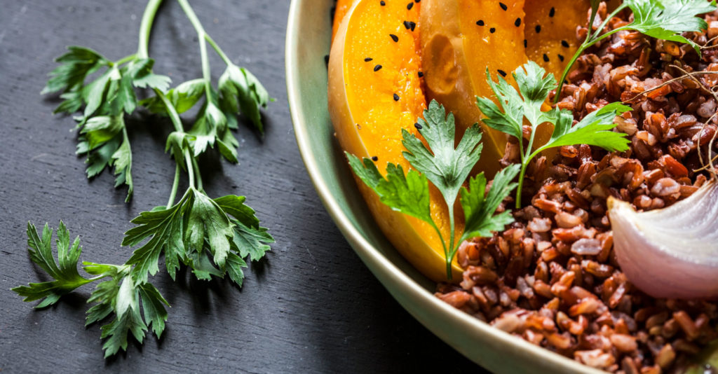 a close up photo of herbs and a healthy dish containing beans and orange vegetables