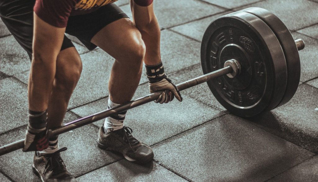 a person with gloves lifting a heavy barbell in a gym