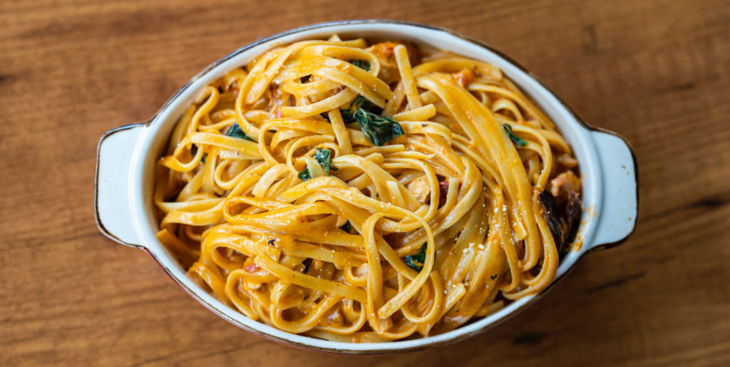 a top down photo of a pasta dish high in carbohydrates on a wood table