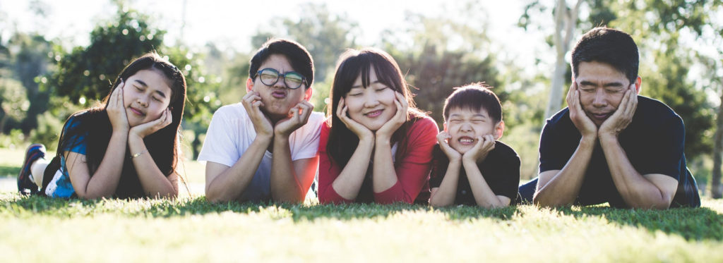 a family of 5 lying together on the grass