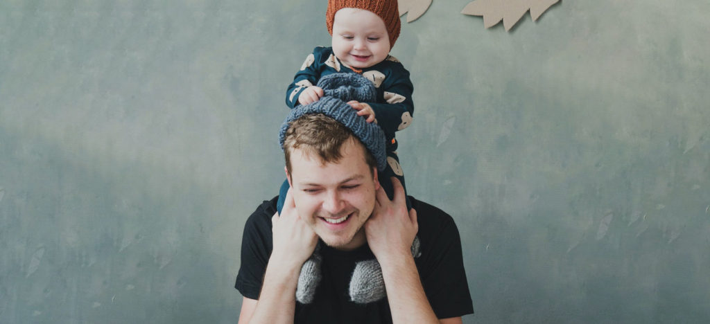 a man standing with his infant son up on his shoulders