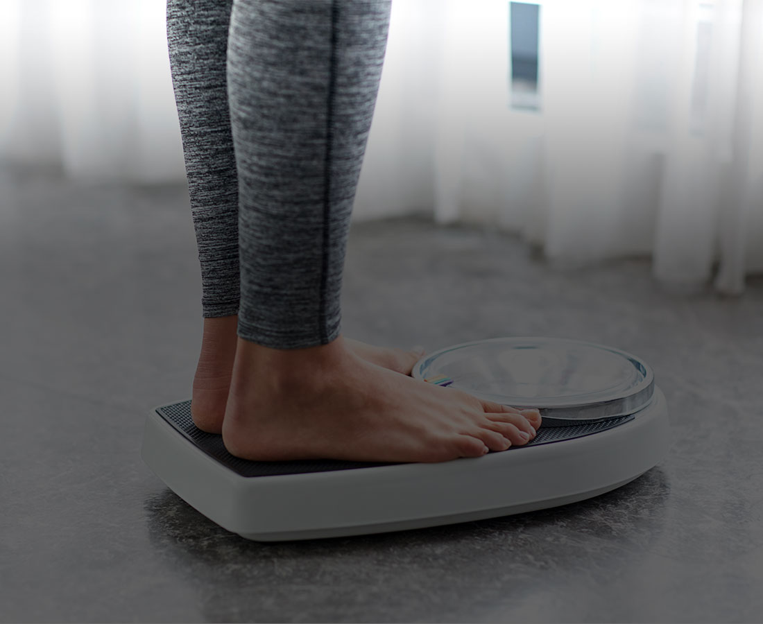 a cropped photo of a person standing on top of weight scales