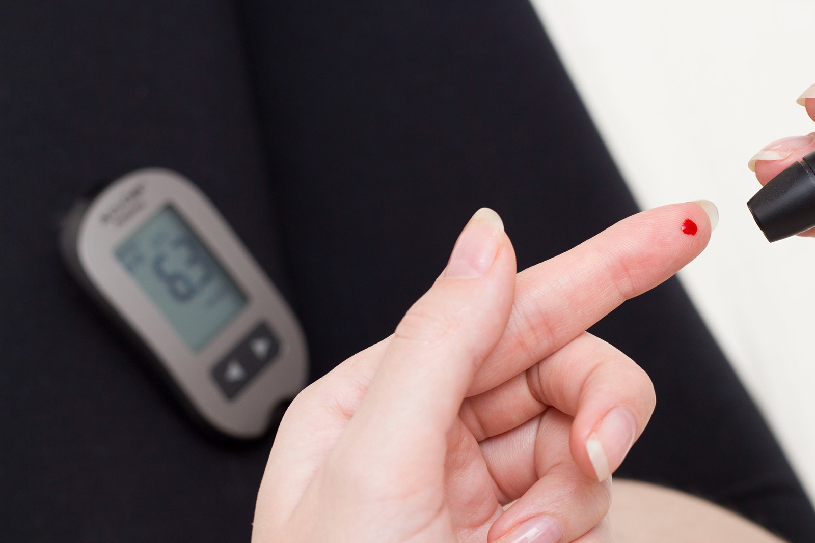 Blood Glucose Levels a person performing a finger prick with a drop of blood