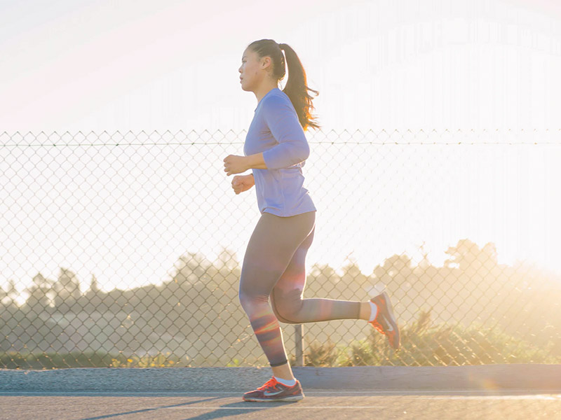 a woman out for a run in sunshine at golden hour