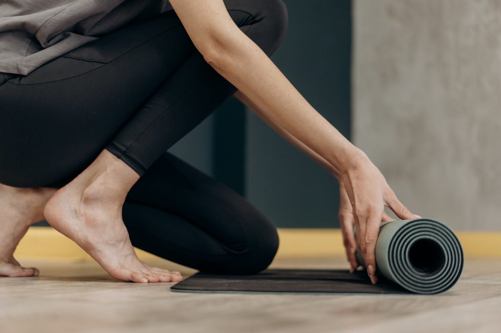 toned woman unrolling yoga mat