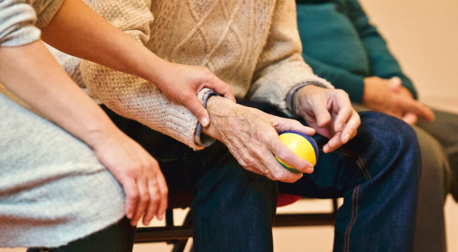 a younger person holding the wrist of an elderly person