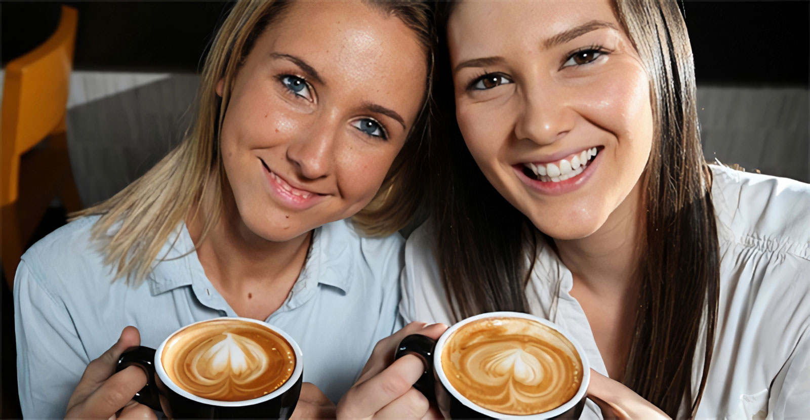 two girls smiling holding cups of coffee