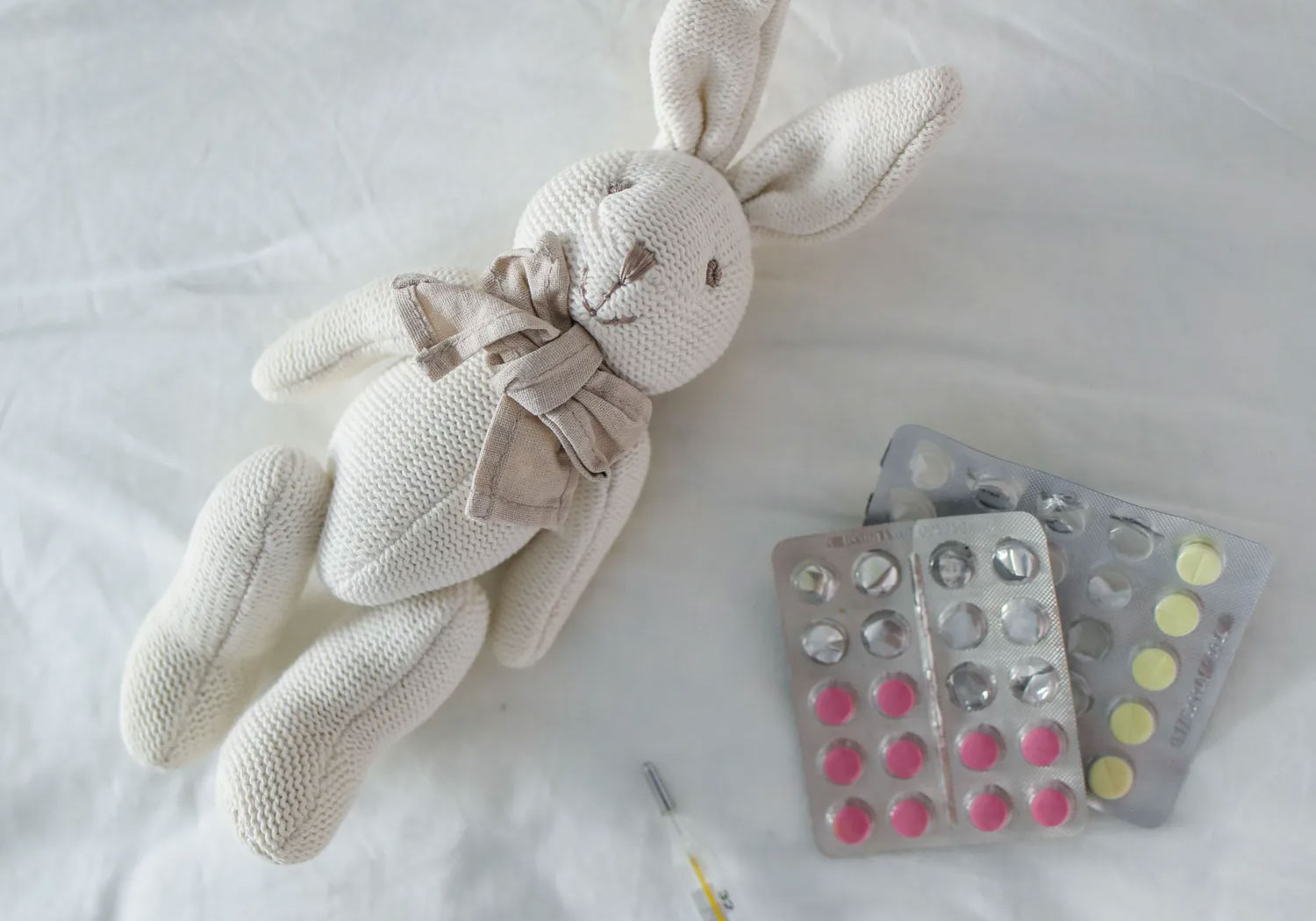 two medication packets on a bed with a comforting soft toy