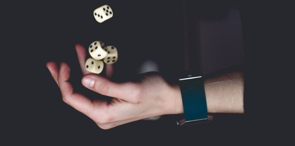 a person wearing a blue wristwatch tossing dice into the air