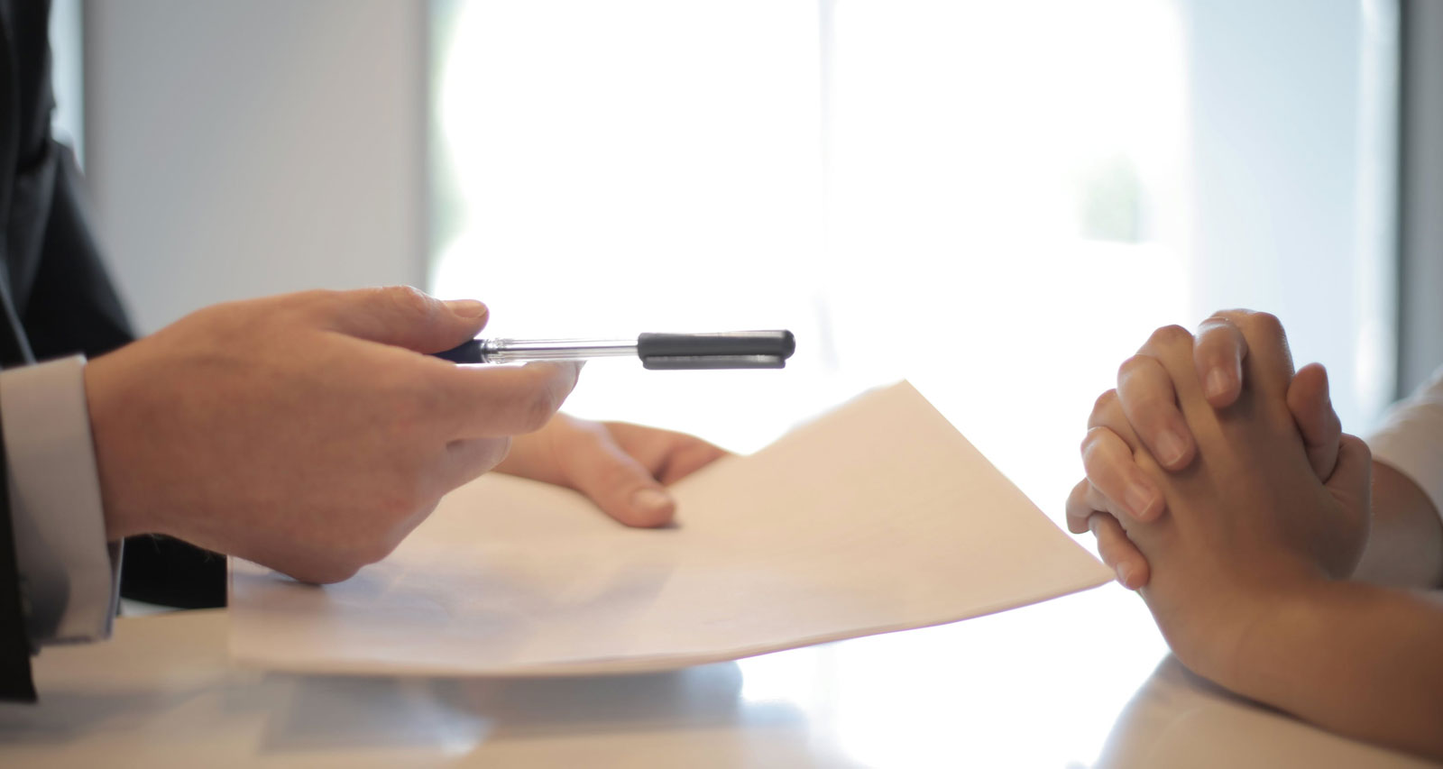 a person in a suit holding a pen and paper discussing insurance with another person