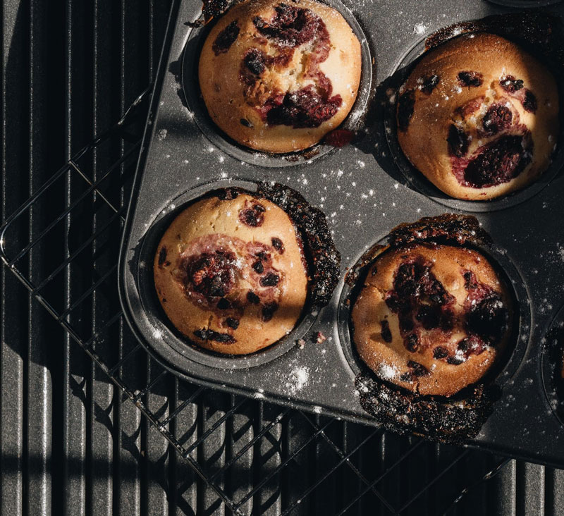 some freshly baked muffins in a tray dusted with icing sugar