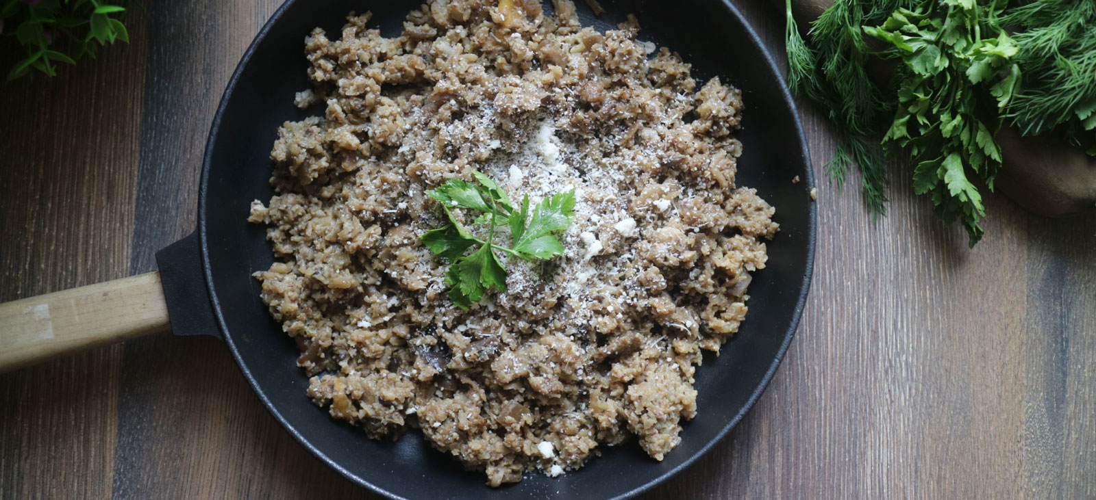 a black pan with a keto meal garnished with herbs on a wooden table