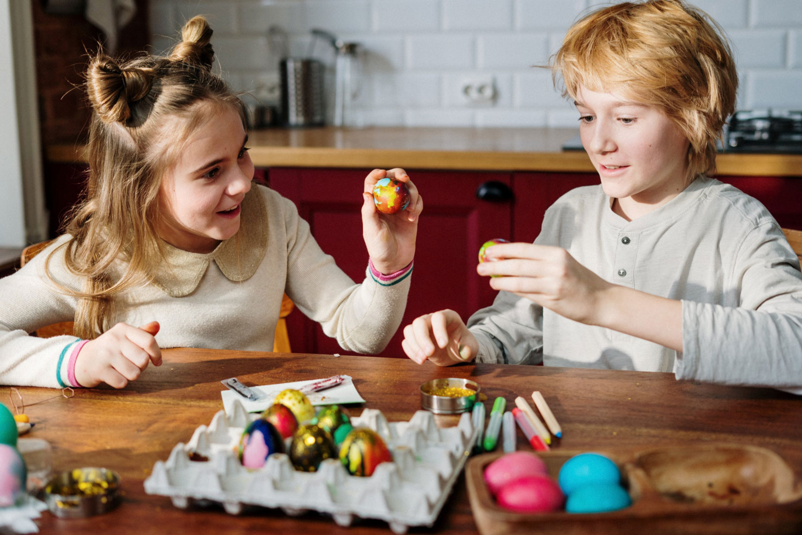 two young kids painting and decorating eggs