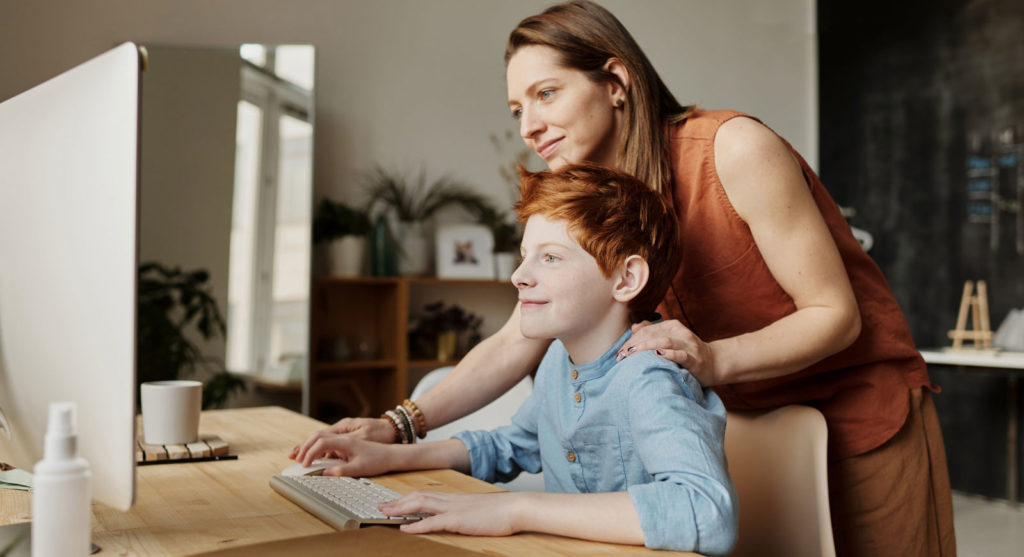 a woman and her son looking at a computer screen