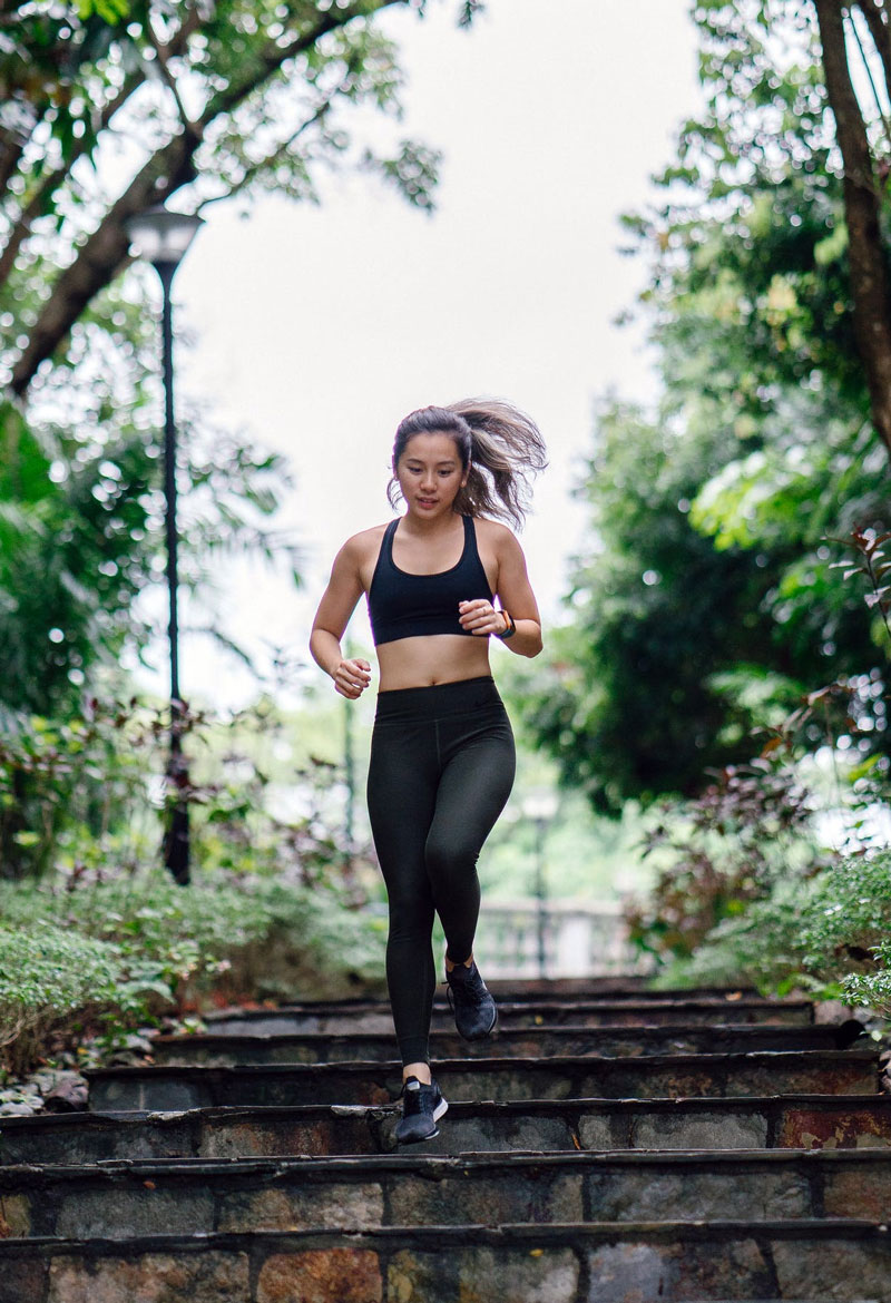 a woman in sports gear running down brick stairs