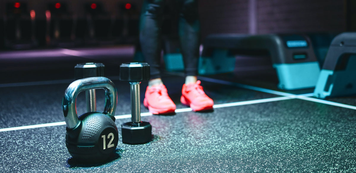 a person standing next to dumbbells and a kettlebell in a gym