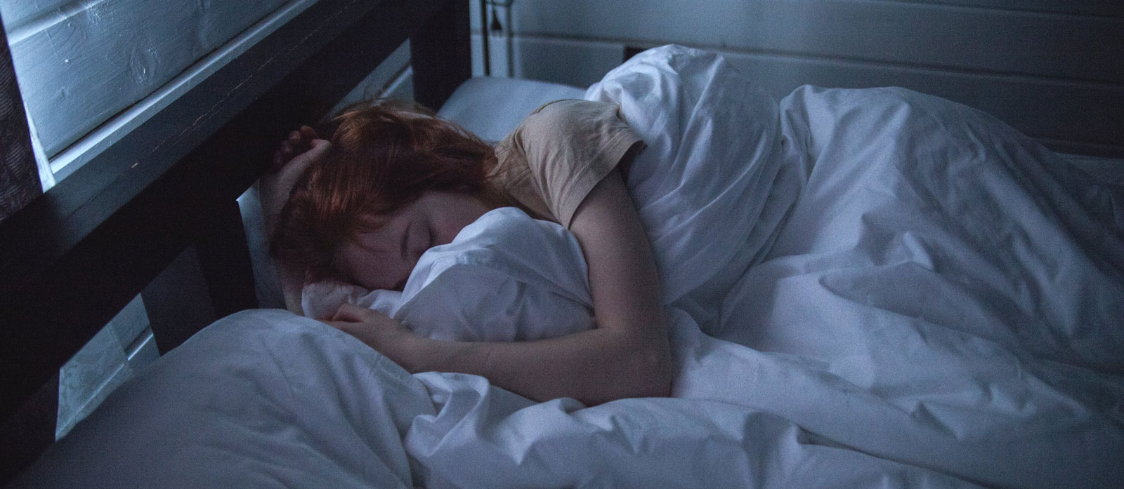 A red-haired woman asleep in a darkened room