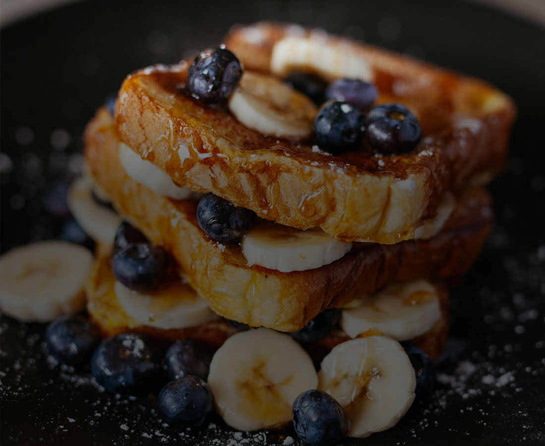 a close up shot of blueberries and bananas on waffles