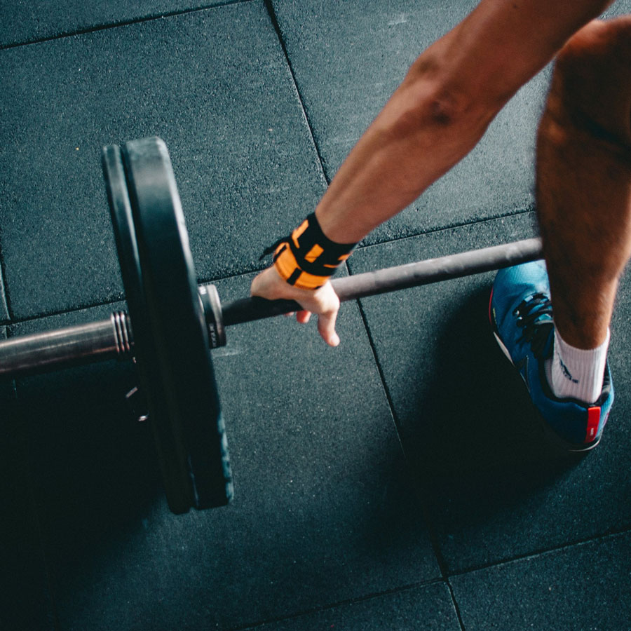 a close up shot of a man grabbing a barbell on a gym floor