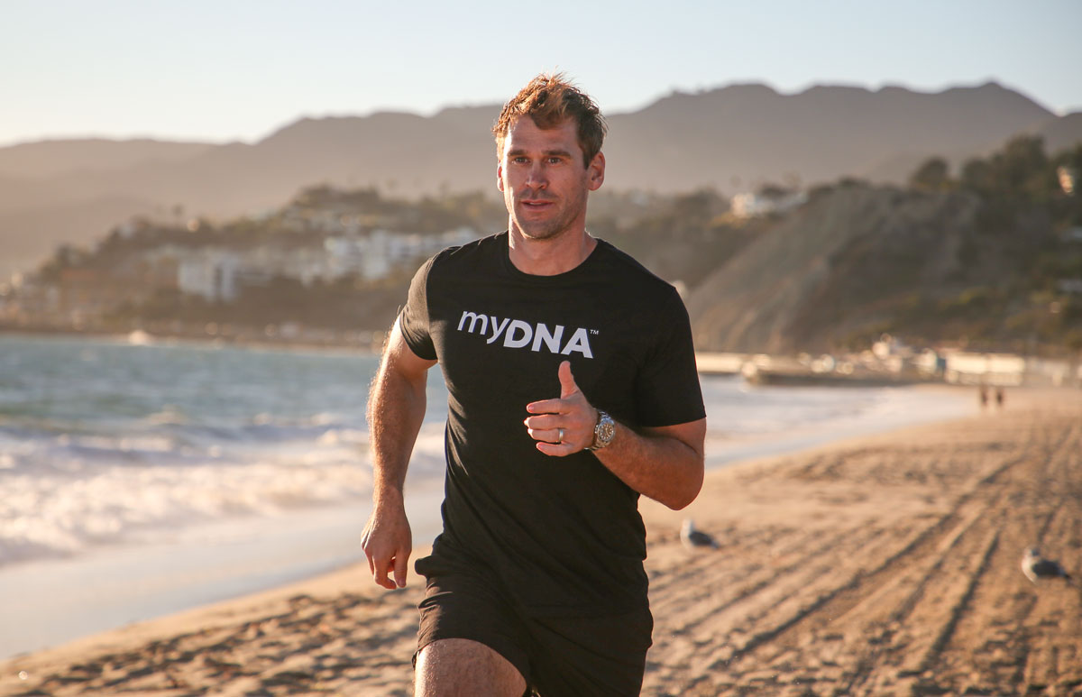 Luke Milton running on the beach wearing a black myDNA top