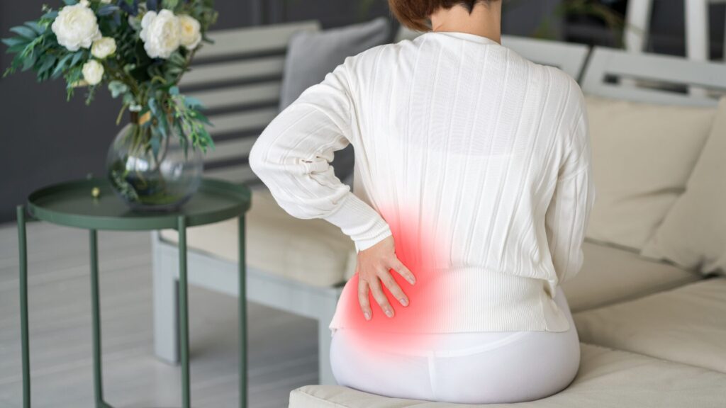 Person grasping hip due to lower back pain.