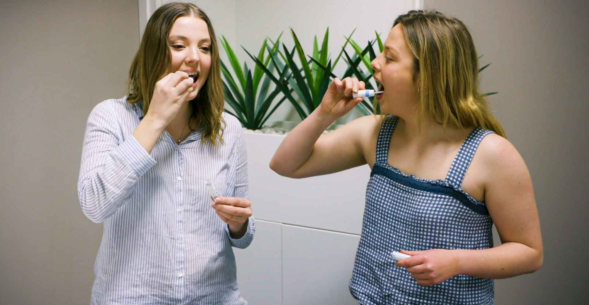 Two sisters swabbing the inside of their cheeks