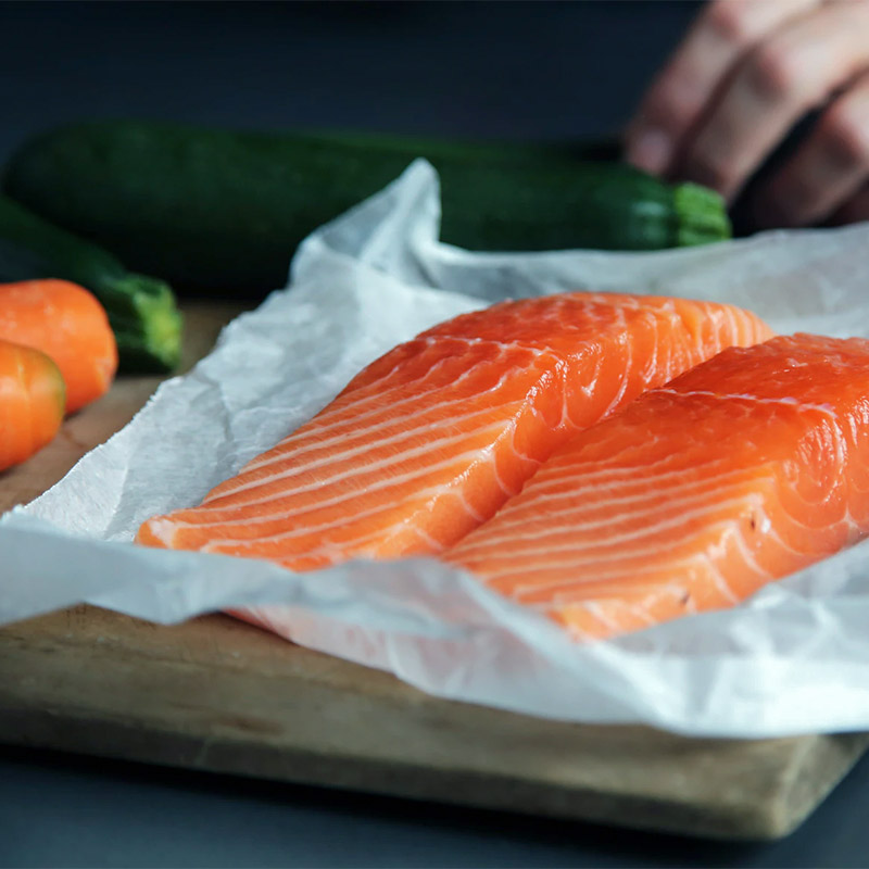 two fillets of salmon on a wooden chopping board