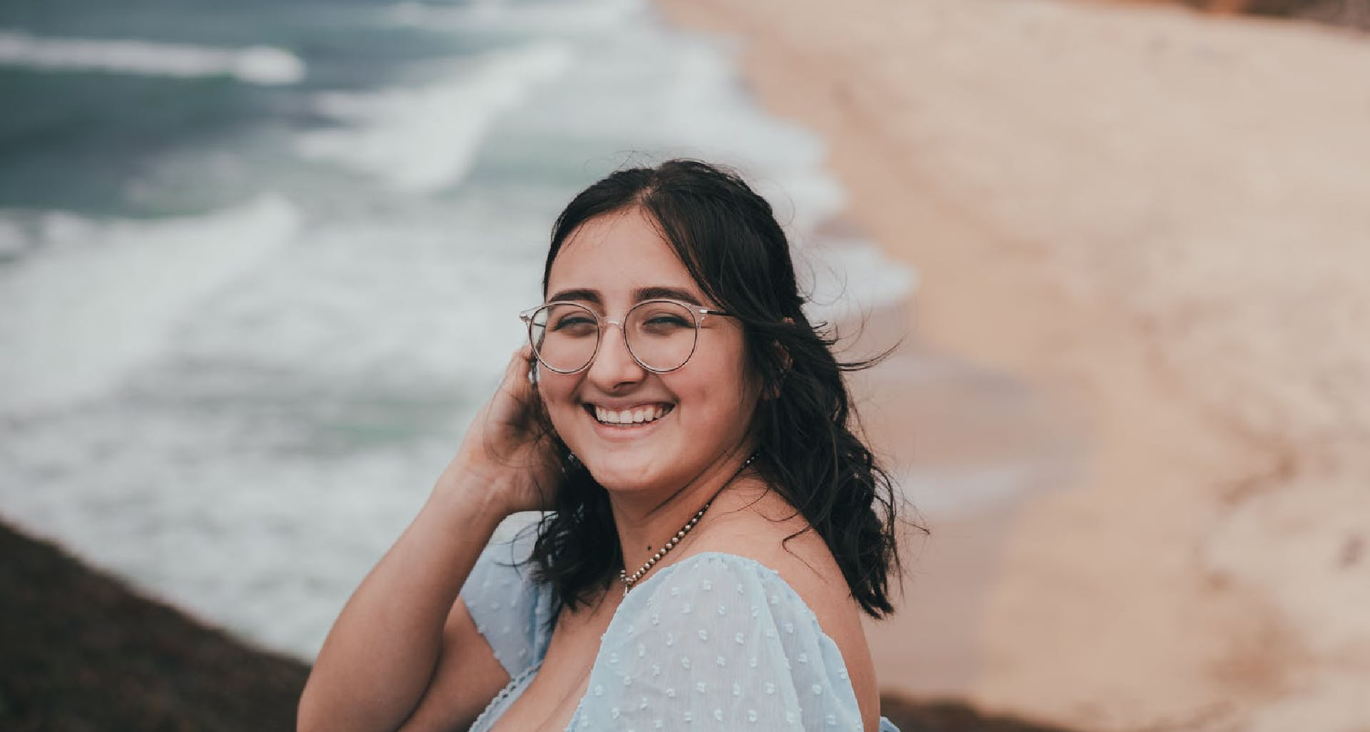 a woman smiling outdoors near a beach